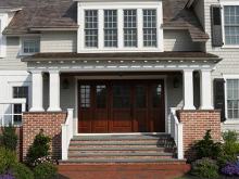 classic wide mahogany entryway exterior with brick foundation and herirngbone brick walkway