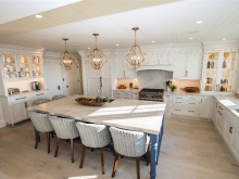 Country style warm white wood kitchen with bold brass lighting pendants and lighted glass cabinets