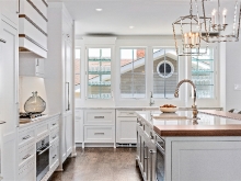 Elegant white wood and natural wood kitchen with large island, detailed stove hood  and two sink prep areas