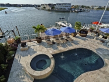 Organic shaped pool and hot tub, travertine surround facing dock and bay for sunset views